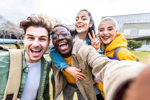 Middelbare scholieren van allerlei afkomsten lachen met elkaar voor de school