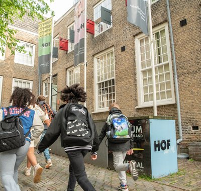 Schoolkinderen rennen over het plein van Hof van Nederland