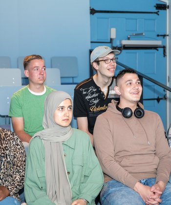 Een groep van zes jongeren bekijkt in de filmzaal in Hof van Nederland de film. Ze staan vanaf het vooraanzicht op de foto.