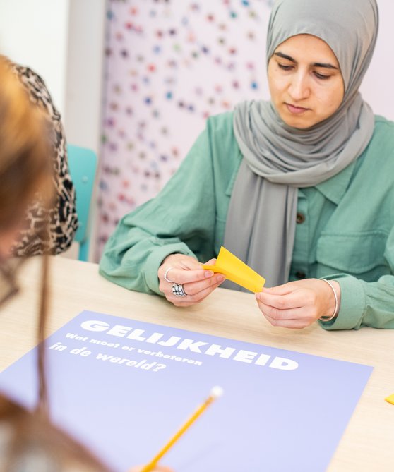 Een leerling zit aan tafel en is bezig met de museumles in Hof van Nederland.