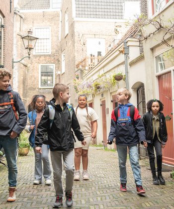 Een groep kinderen loopt in de smalle straatjes bij Hof van Nederland