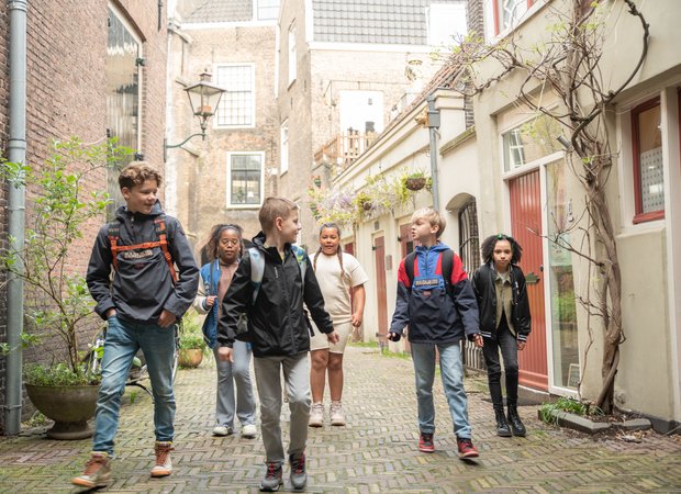 Een groep kinderen loopt in de smalle straatjes bij Hof van Nederland