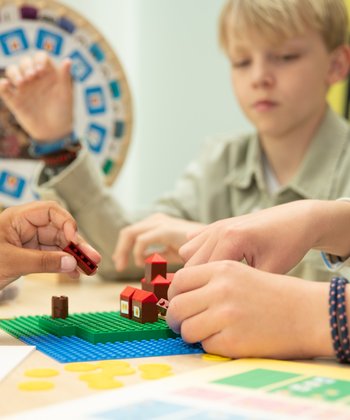 Kinderen aan een tafel bouwen met LEGO een middeleeuwse stad