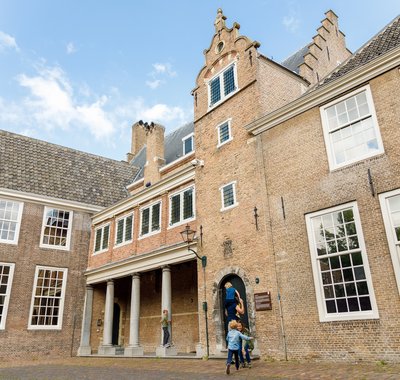 Rennende kinderen op het plein. Ze gaan met een volwassene mee naar binnen in het museum.