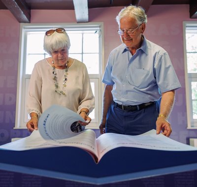 Een oudere man en vrouw bladeren door een boek in het museum.