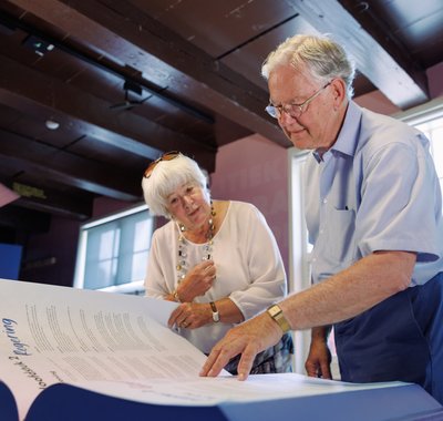 Een oudere man en vrouw bladeren door een boek in het museum