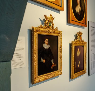Een wand met schilderijen van personen in het museum.