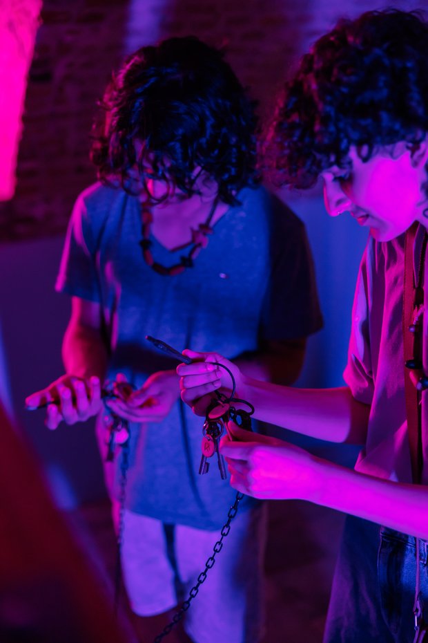 Jonge man en vrouw zoeken naar de juiste sleutel in een donkere escaperoom.