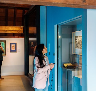 In een voornamelijk blauwe museumzaal bekijken een man en vrouw de voorwerpen en schilderijen.