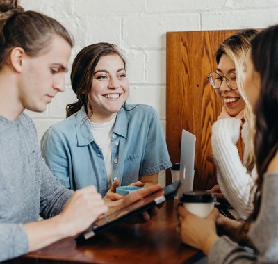Een groep vrienden aan het studeren en lachen in een lunchcafé.